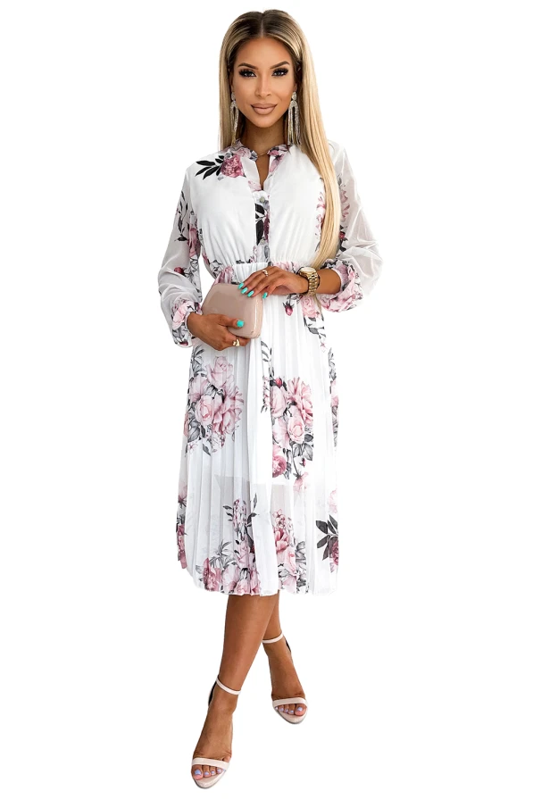Rochia plisată Carla este de culoare albă cu imprimeu floral roz și negru, având mâneci lungi și un design elegant. Materialul ușor și croiala feminină o fac ideală pentru ocazii speciale.