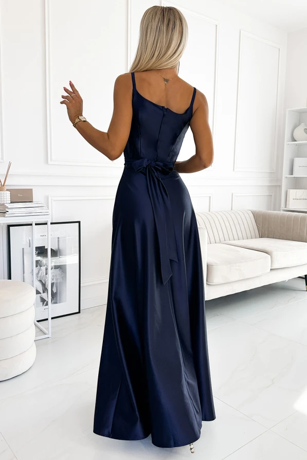 Rochia elegantă, lungă, de culoare albastru închis, are un design fără mâneci și bretele subțiri, accentuând talia cu o panglică delicată la spate. Materialul lucios și croiala fluidă oferă un aspect sofisticat și rafinat, ideal pentru evenimente speciale.