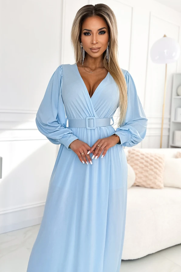 Rochia lungă albastră Fiorella are un design elegant cu decolteu în V și mâneci lungi bufante. Cureaua lată accentuează talia, oferind o siluetă sofisticată și feminină.